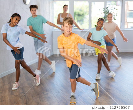 Boy exercising in group of classmates during dance class at dance studio 112756507