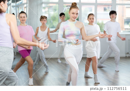 Young girls and boys repeat the movements of dance teacher, training in spacious studio 112756511