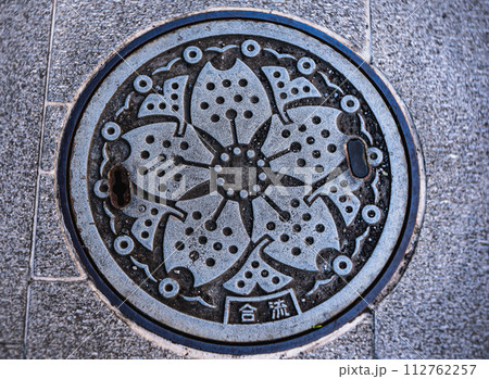 桜がデザインされた下水道の鉄蓋が設置されている風景 112762257