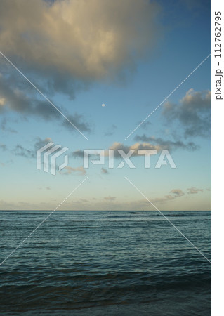 朝焼けしている空に浮かぶ月と穏やかな波 朝焼けしている空に浮かぶ月と穏やかな波 112762795