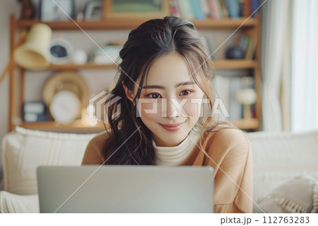 リビングでノートパソコンを使う若い女性 リビングでノートパソコンを使う若い女性 112763283