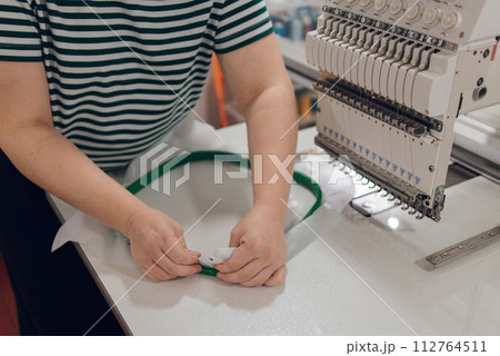 girl seamstress doing embroidery puts fabric in a special hoop, hobby and work from home 112764511