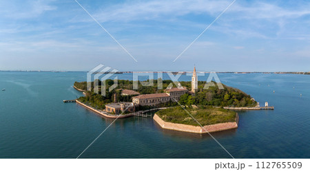 Aerial view of the plagued ghost island of Poveglia in the Venetian lagoon, opposite Malamocco along the Canal Orfano near Venice, Italy. Aerial view of the plagued ghost island of Poveglia in the Venetian lagoon, opposite Malamocco along the Canal Orfano near Venice, Italy. 112765509
