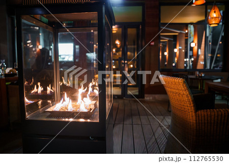 A luxurious lounge in Engelberg with a modern glass fireplace, wicker chairs, and elegant lighting, offering a warm, inviting space for relaxation after skiing. A luxurious lounge in Engelberg with a modern glass fireplace, wicker chairs, and elegant lighting, offering a warm, inviting space for relaxation after skiing. 112765530