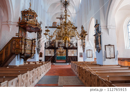 Bright, airy church in Copenhagen or Malmo with white walls, arched ceilings, and a central aisle to a blue altar. Boasts a grand chandelier, carved wooden pulpit, and orderly pew rows. Bright, airy church in Copenhagen or Malmo with white walls, arched ceilings, and a central aisle to a blue altar. Boasts a grand chandelier, carved wooden pulpit, and orderly pew rows. 112765915