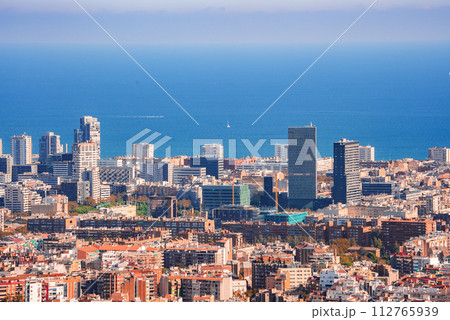 Panoramic daytime view of Barcelona's urban landscape, showcasing a blend of modern and traditional architecture with the Mediterranean Sea in the background. 112765939