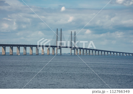 Capturing the iconic Oresund Bridge, this image features its high pylons and sleek design, linking Copenhagen, Denmark, with Malmo, Sweden, under a partly cloudy sky. Capturing the iconic Oresund Bridge, this image features its high pylons and sleek design, linking Copenhagen, Denmark, with Malmo, Sweden, under a partly cloudy sky. 112766349