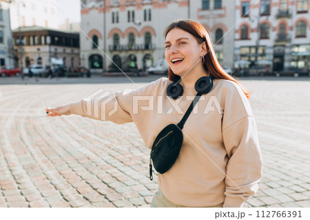Stylish 30s woman with bag catching a taxi. Happy cheerful young woman walking on city street, Urban lifestyle concept. Traveler 112766391
