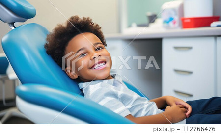 Smiling African American boy sitting in dentist's chair, kids teeth care, pediatric dentistry office for children, happy child ready for teeth checkup, first dental visit to pedodontist 112766476