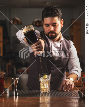 Bartender pouring craft cocktail at bar 112767145