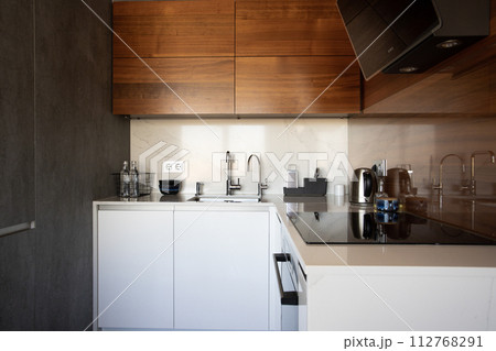 Kitchen brass utensils, chef accessories. Hanging modern kitchen with white marble wall and stone tabletop. 112768291