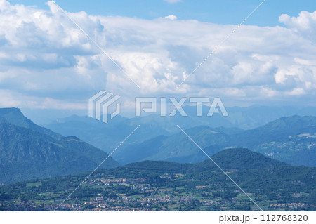 Beautiful landscape of the layered misty hazy Italian Alps mountain range during evening. Lombardy, Italy Beautiful landscape of the layered misty hazy Italian Alps mountain range during evening. Lombardy, Italy 112768320