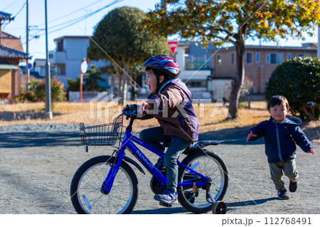 公園で自転車に乗る男の子と後を追う弟 112768491