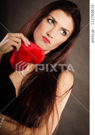 Sad lovely woman holds red heart on black 112768619