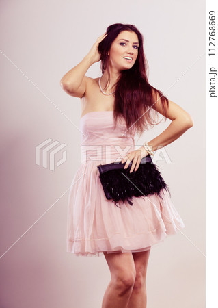 Brunette woman in bright dress with clutch bag 112768669