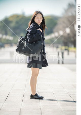 立ってカメラを見つめる女子高生と冬の街並み 112768831