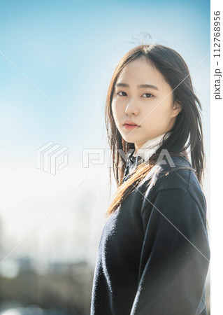 青空のもと未来を見据える女子高校生 112768956