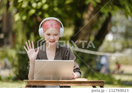 Young woman with a laptop and notes studying in the park for education in nature to relax and learn online. Young woman with a laptop and notes studying in the park for education in nature to relax and learn online. 112769023