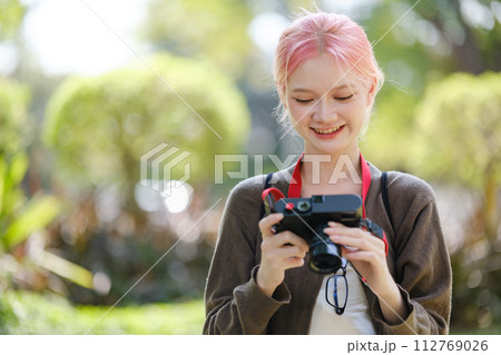 Beautiful Young artist Woman taking photo in flowers garden. Young cute girl carry the camera in the garden. Beautiful Young artist Woman taking photo in flowers garden. Young cute girl carry the camera in the garden. 112769026