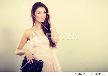 Brunette woman in bright dress with clutch bag 112769587