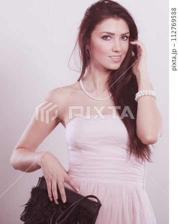 Brunette woman in bright dress with clutch bag Brunette woman in bright dress with clutch bag 112769588