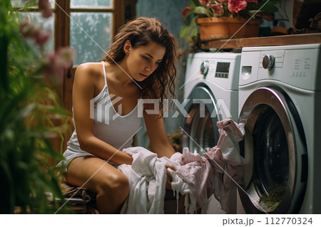 Young woman in a casual outfit sorting clothes for washing in a cozy laundry room Young woman in a casual outfit sorting clothes for washing in a cozy laundry room 112770324