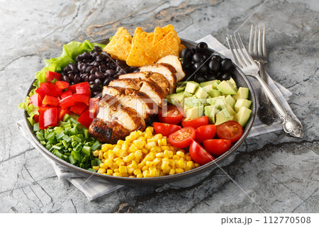 Southwest salad of chicken, corn, peppers, olives, avocado, tomatoes and onions close-up on a board. Horizontal Southwest salad of chicken, corn, peppers, olives, avocado, tomatoes and onions close-up on a board. Horizontal 112770508