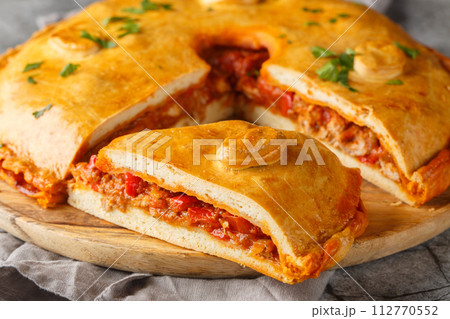 Delicious Empanada Gallega round Spanish pie filled with meat and vegetables close-up on a board. Horizontal 112770552