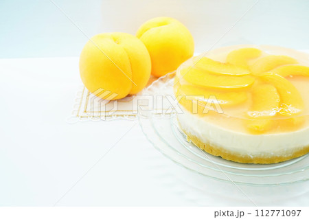 白背景に黄桃を飾った二層の涼し気なレアチーズケーキのホール 白背景に黄桃を飾った二層の涼し気なレアチーズケーキのホール 112771097