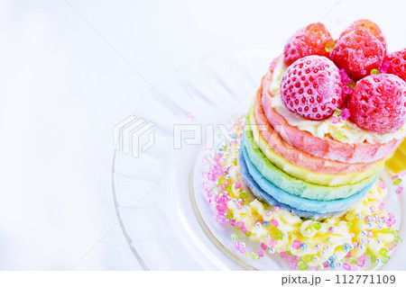 シンプルな白背景に赤いいちごの乗ったキラキラした可愛いレインボーケーキ、俯瞰 シンプルな白背景に赤いいちごの乗ったキラキラした可愛いレインボーケーキ、俯瞰 112771109