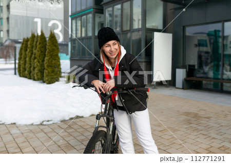 Young woman in winter clothes riding a bicycle 112771291