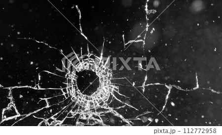 Close-up of gunshot through the glass, shattering against the black background 112772958