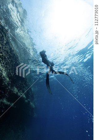 Freediver Swimming in Deep Sea With Sunrays. Young Man Diver Eploring Sea Life. 112773010