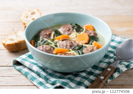 Italian Wedding Soup with meatballs and spinach on wooden table Italian Wedding Soup with meatballs and spinach on wooden table 112774506