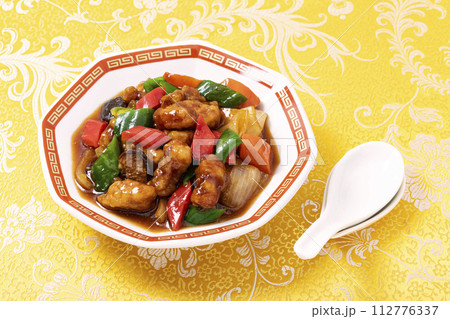 黄色い中華柄の布地を敷き八角皿に盛りつけた中華料理の定番メニュー酢豚 黄色い中華柄の布地を敷き八角皿に盛りつけた中華料理の定番メニュー酢豚 112776337