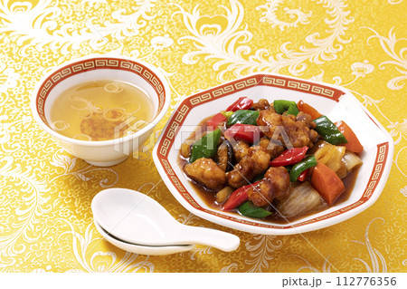 黄色い中華柄の布地を敷き八角皿に盛りつけた中華料理の定番メニュー酢豚 黄色い中華柄の布地を敷き八角皿に盛りつけた中華料理の定番メニュー酢豚 112776356