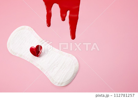 Blood, feminine hygiene pad with red heart on pink background. First menstrual period concept, menstruation cycle period 112781257