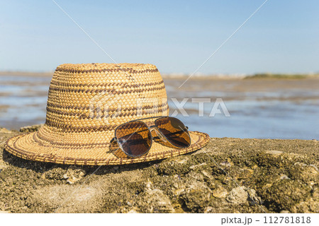Straw hat and sunglasses on a beach Straw hat and sunglasses on a beach 112781818