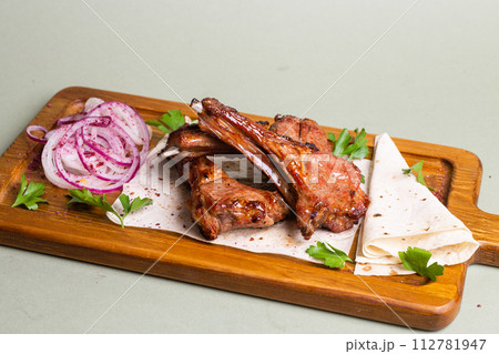 Grilled lamb ribs with herbs and spices on a wooden board 112781947