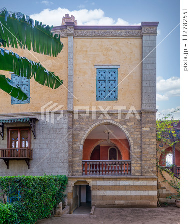 Serene view of a rustic style building featuring an arched wooden balcony, and detailed window grills Serene view of a rustic style building featuring an arched wooden balcony, and detailed window grills 112782551