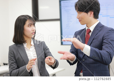 高さを示し話すビジネスマンと疑問を持つビジネスウーマン_1 高さを示し話すビジネスマンと疑問を持つビジネスウーマン_1 112782885
