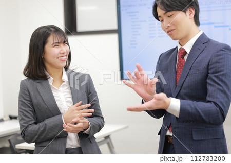 自分の考えを話すビジネスマンと微笑むビジネスウーマン_1 112783200