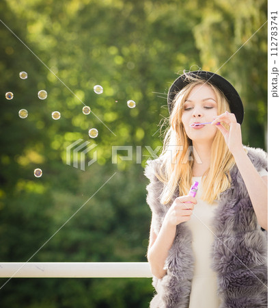 Joyful teen woman blowing bubbles 112783741