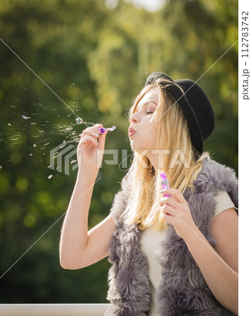 Joyful teen woman blowing bubbles 112783742