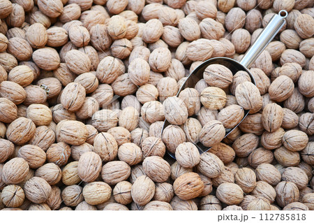 A scoop of walnuts, a superfood, rests on a stack of nuts seeds 112785818