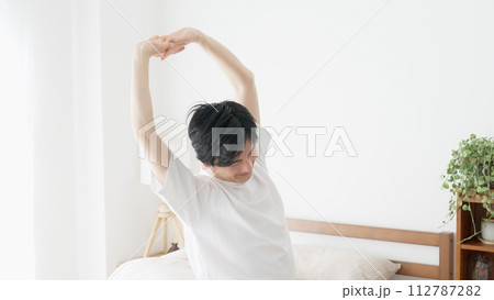 目覚めて伸びをする男性 112787282