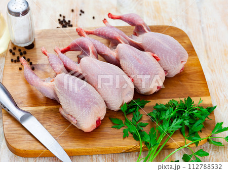Raw gutted partridges on wooden table with seasonings and greens Raw gutted partridges on wooden table with seasonings and greens 112788532