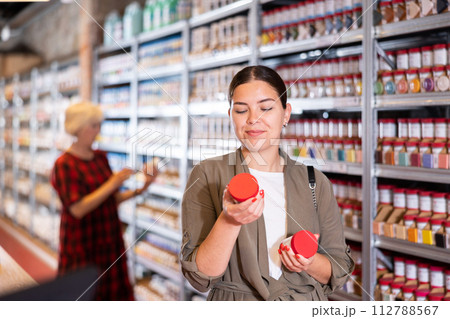 Female shopper choosing pottery glaze jars in pottery specialty store Female shopper choosing pottery glaze jars in pottery specialty store 112788567