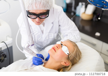 Cosmetologist using laser to resurface skin of young woman's face Cosmetologist using laser to resurface skin of young woman's face 112788718