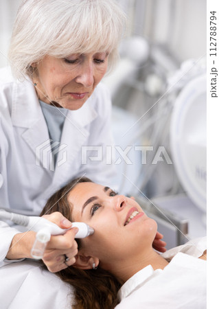Elderly female beautician doing procedure of microneedling, mesotherapy for young woman in beauty salon indoors Elderly female beautician doing procedure of microneedling, mesotherapy for young woman in beauty salon indoors 112788794
